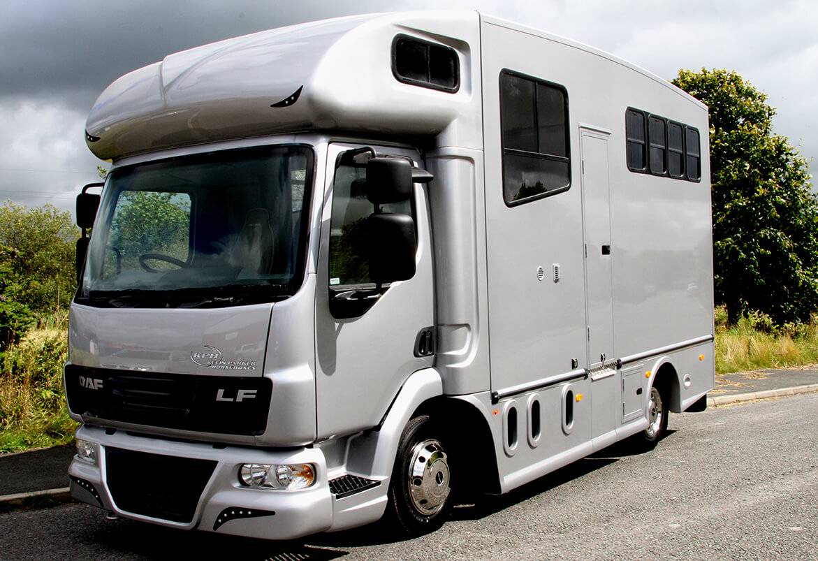 A large grey horsebox parked at the side of a road