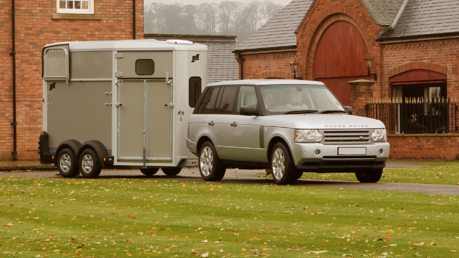 A car towing a horse trailer out of a yard