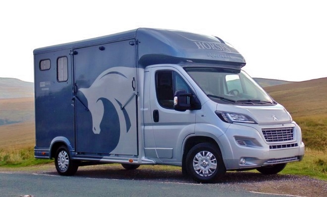 A horsebox parked on a road in a mountainous region