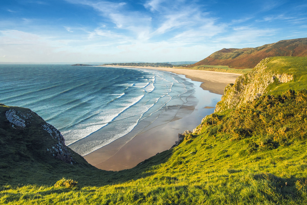 A bay on the Welsh coast surrounded by hills as the sunsets