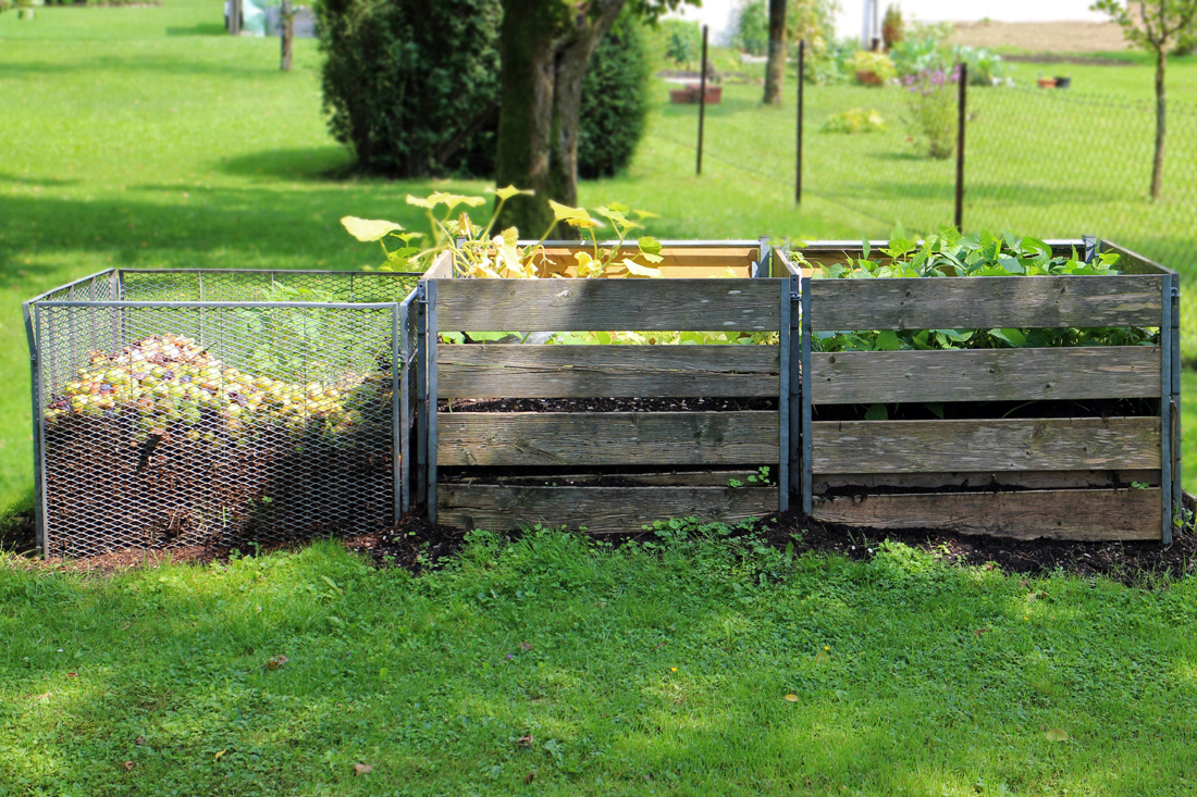 Three compost bins in a grassy field