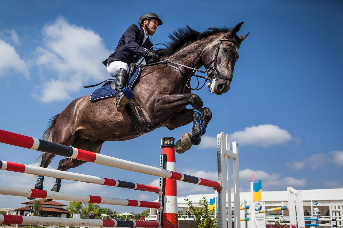 A horse and rider jumping a fence at a show