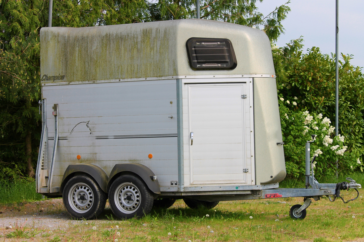 A slightly dirty horse trailer parked in a field