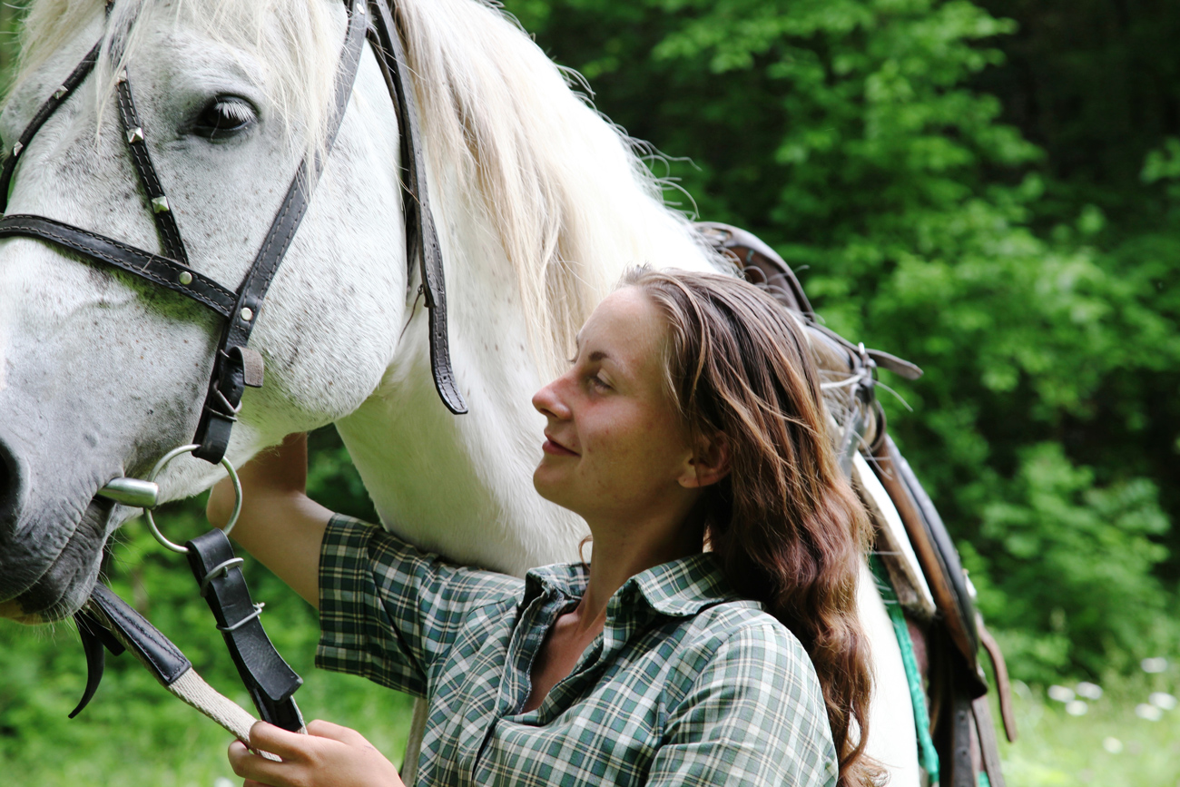 A woman walking with a horse holding its reins