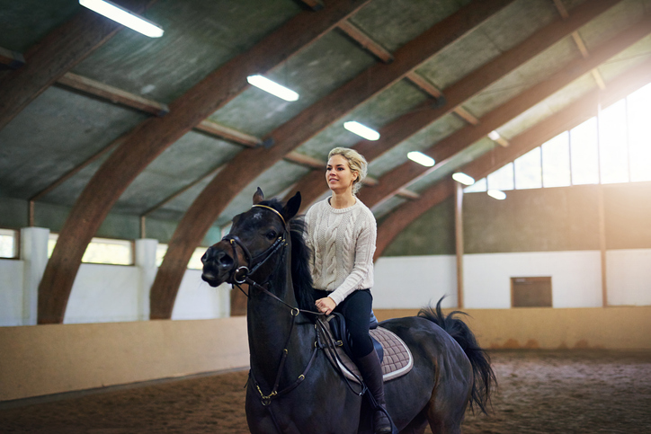 A woman riding a horse in an arena