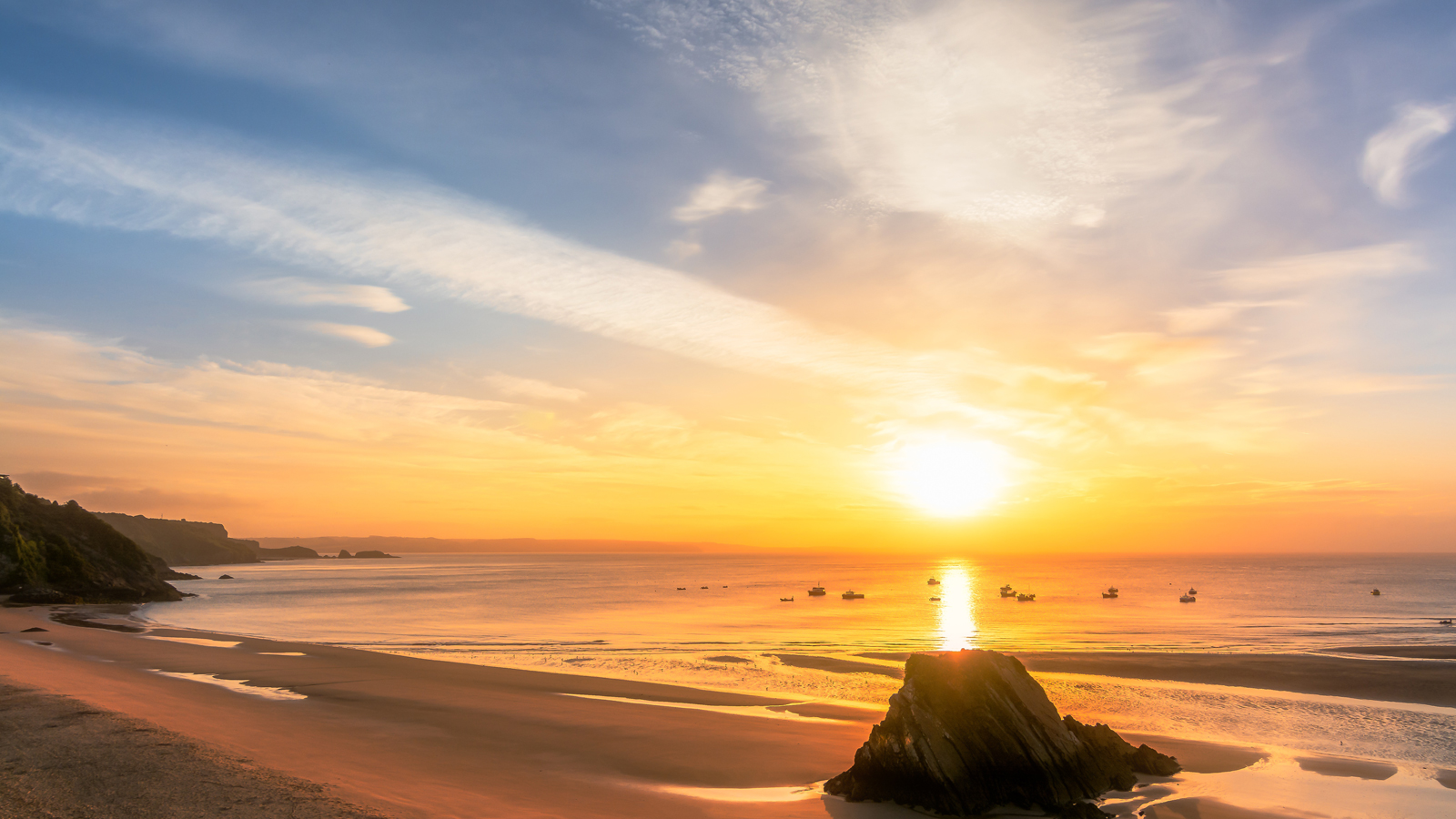 A view of the sun setting over a sandy beach